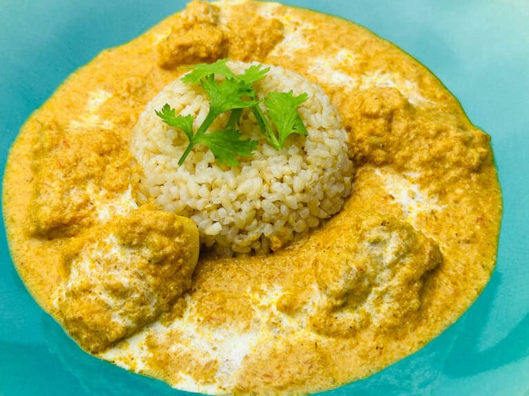 Koji-marinated butter chicken served with brown rice and fresh Italian parsley on a teal plate.